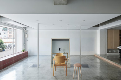 Imagen de estudio minimalista de tamaño medio sin chimenea con paredes blancas, suelo de cemento, escritorio independiente y suelo gris