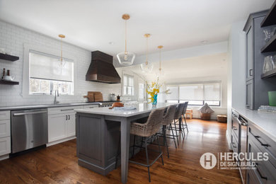 Example of a large transitional medium tone wood floor and brown floor open concept kitchen design in St Louis with an undermount sink, shaker cabinets, gray cabinets, quartz countertops, white backsplash, subway tile backsplash, stainless steel appliances, an island and white countertops