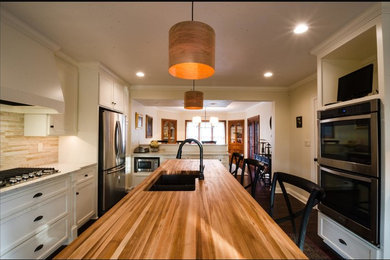 Eat-in kitchen - mid-sized traditional u-shaped dark wood floor and brown floor eat-in kitchen idea in Other with an undermount sink, shaker cabinets, white cabinets, marble countertops, beige backsplash, travertine backsplash, stainless steel appliances and an island