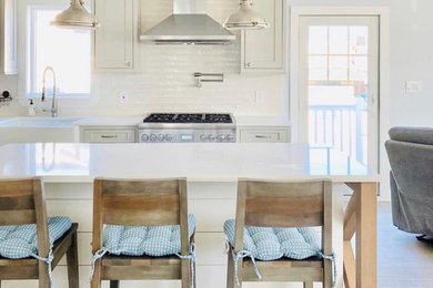 Example of a mid-sized transitional l-shaped porcelain tile and beige floor eat-in kitchen design in New York with a farmhouse sink, shaker cabinets, gray cabinets, quartz countertops, white backsplash, subway tile backsplash, stainless steel appliances, an island and white countertops