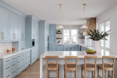 Large u-shaped light wood floor enclosed kitchen photo in Jacksonville with an undermount sink, beaded inset cabinets, blue cabinets, quartz countertops, white backsplash, ceramic backsplash, colored appliances, a peninsula and white countertops