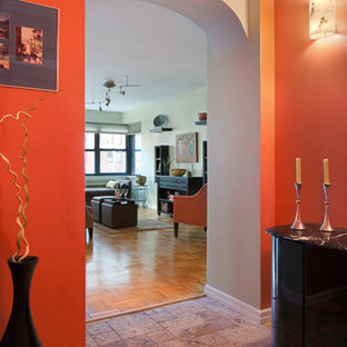 Cette image montre un petit hall d'entrée bohème avec un mur orange, un sol en marbre et une porte simple.