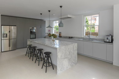 This is an example of a large contemporary l-shaped kitchen/diner in London with a submerged sink, flat-panel cabinets, grey cabinets, quartz worktops, stainless steel appliances, ceramic flooring, an island and grey floors.