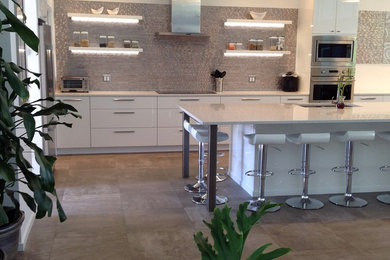 Eat-in kitchen - large 1960s single-wall porcelain tile eat-in kitchen idea in Burlington with an undermount sink, flat-panel cabinets, white cabinets, quartz countertops, multicolored backsplash, stainless steel appliances, an island and metal backsplash