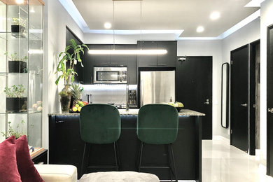 Small trendy galley porcelain tile and white floor open concept kitchen photo in Toronto with an undermount sink, flat-panel cabinets, black cabinets, granite countertops, white backsplash, marble backsplash, stainless steel appliances, a peninsula and gray countertops