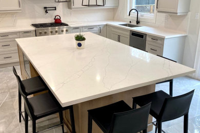 Mid-sized transitional l-shaped porcelain tile open concept kitchen photo in Toronto with an undermount sink, shaker cabinets, gray cabinets, quartz countertops, white backsplash, quartz backsplash, stainless steel appliances, an island and white countertops