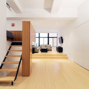 Idee per un piccolo soggiorno minimalista stile loft con pareti bianche, pavimento in bambù e TV a parete