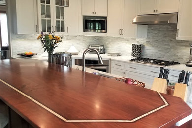 Example of a mid-sized transitional l-shaped porcelain tile and beige floor kitchen pantry design in Other with an undermount sink, shaker cabinets, white cabinets, quartz countertops, multicolored backsplash, glass sheet backsplash, stainless steel appliances, an island and white countertops