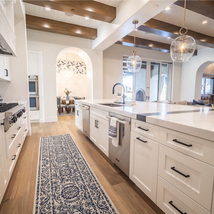 This contemporary home remodel was so fun for the MFD Team! This white kitchen features exposed wood beams, medium washed hardwood flooring, and stainless steel appliances. The open concept design spa