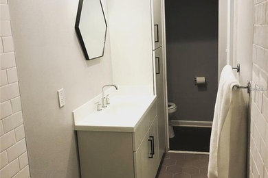 Inspiration for a small mid-century modern master white tile and subway tile porcelain tile and gray floor bathroom remodel in Orlando with flat-panel cabinets, white cabinets, a one-piece toilet, gray walls, an integrated sink, solid surface countertops and white countertops