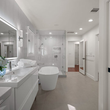 Walk-in glass shower with warm tile flooring