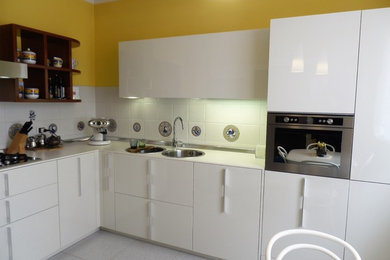 Foto di una cucina minimalista chiusa e di medie dimensioni con lavello a doppia vasca, ante lisce, ante bianche, top in superficie solida, paraspruzzi a effetto metallico, paraspruzzi con piastrelle in ceramica, elettrodomestici in acciaio inossidabile, pavimento in gres porcellanato, pavimento grigio e top bianco