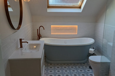 This is an example of a large contemporary family bathroom in Hertfordshire with recessed-panel cabinets, a freestanding bath, a walk-in shower, a two-piece toilet, white tiles, ceramic tiles, cement flooring, engineered stone worktops, multi-coloured floors, an open shower, white worktops, a wall niche, a single sink and a floating vanity unit.