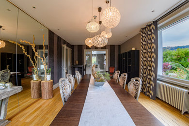 Exemple d'une très grande salle à manger chic avec un mur gris, un sol en bois brun et une cheminée standard.