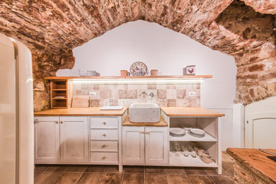 Idee per una cucina lineare mediterranea chiusa e di medie dimensioni con lavello stile country, ante in stile shaker, ante bianche, top in legno, paraspruzzi beige, paraspruzzi in gres porcellanato, elettrodomestici colorati e pavimento in terracotta