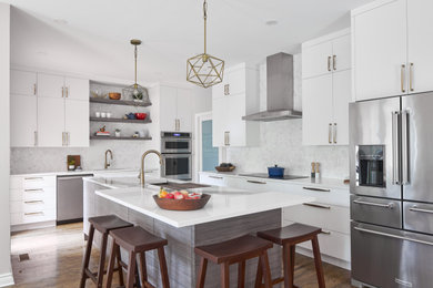 Example of a trendy l-shaped dark wood floor and brown floor kitchen design in Other with an undermount sink, flat-panel cabinets, white cabinets, white backsplash, stainless steel appliances, an island and white countertops