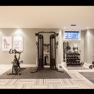 Large modern home weight room in New York with grey walls and carpet.