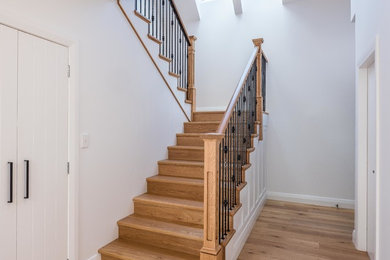 Mid-sized traditional wood u-shaped staircase in Wellington with wood risers and metal railing.