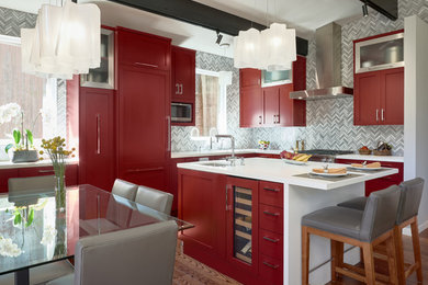 This is an example of a contemporary l-shaped eat-in kitchen in San Francisco with an undermount sink, shaker cabinets, red cabinets, panelled appliances, dark hardwood floors, with island, brown floor and white benchtop.