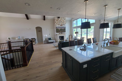 Inspiration for a large open concept medium tone wood floor and exposed beam living room remodel in Salt Lake City with beige walls, a standard fireplace, a stone fireplace and a wall-mounted tv