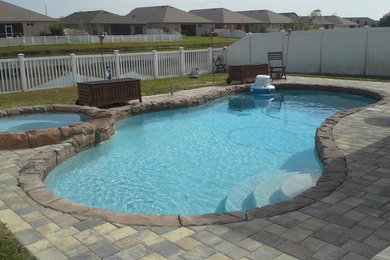 Large island style backyard brick and custom-shaped natural hot tub photo in Tampa