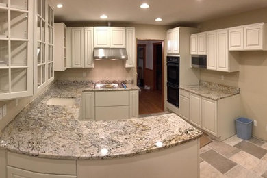 Example of a mid-sized transitional u-shaped ceramic tile eat-in kitchen design in New York with glass-front cabinets, white cabinets, granite countertops and a peninsula