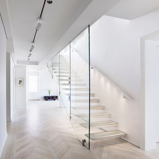 This is an example of a medium sized contemporary glass floating wood railing staircase in New York with open risers.