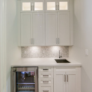 トロントの小さいトランジショナルスタイルのおしゃれなウェットバー (シェーカースタイル扉のキャビネット、グレーのキッチンパネル、淡色無垢フローリング、アンダーカウンターシンク、白いキャビネット、珪岩カウンター、モザイクタイルのキッチンパネル) の写真