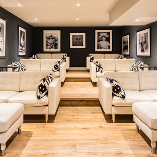 Example of a trendy enclosed light wood floor and brown floor home theater design in Lyon with black walls