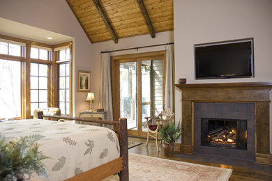 Example of a large classic master medium tone wood floor bedroom design in Other with beige walls, a standard fireplace and a tile fireplace