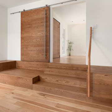 Built-in sofa/ stairs with barn door, with pivot entry door in background
