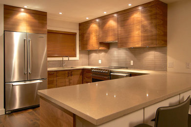 Modern u-shaped eat-in kitchen in Vancouver with an undermount sink, flat-panel cabinets, medium wood cabinets, quartz benchtops, grey splashback, glass tile splashback and stainless steel appliances.