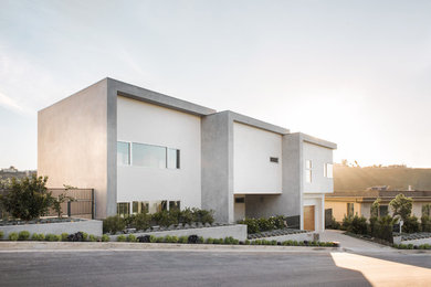 Example of a large minimalist yellow two-story stucco flat roof design in Los Angeles