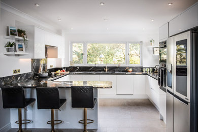 Design ideas for a large contemporary u-shaped eat-in kitchen in Cornwall with a drop-in sink, glass-front cabinets, white cabinets, granite benchtops, multi-coloured splashback, granite splashback, black appliances, cement tiles, a peninsula, beige floor and multi-coloured benchtop.