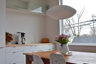 Example of a small trendy galley eat-in kitchen design in Raleigh with flat-panel cabinets, white cabinets, wood countertops and an island