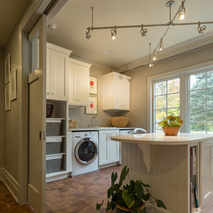 ミルウォーキーの大きいトラディショナルスタイルのおしゃれな家事室 (ドロップインシンク、白いキャビネット、人工大理石カウンター、グレーの壁、コルクフローリング、左右配置の洗濯機・乾燥機) の写真