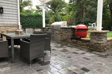 Inspiration for a large contemporary backyard patio in Chicago with an outdoor kitchen, brick pavers and a pergola.