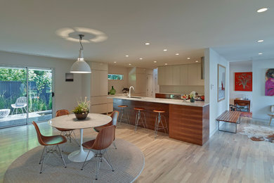 Mid-sized 1950s u-shaped light wood floor eat-in kitchen photo in Oklahoma City with an undermount sink, flat-panel cabinets, medium tone wood cabinets, solid surface countertops, white backsplash, paneled appliances and a peninsula