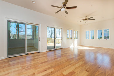 Large trendy light wood floor and brown floor family room photo in Other with white walls