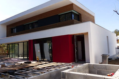 Idées déco pour une grande façade de maison rouge contemporaine en bois à deux étages et plus avec un toit plat et un toit végétal.