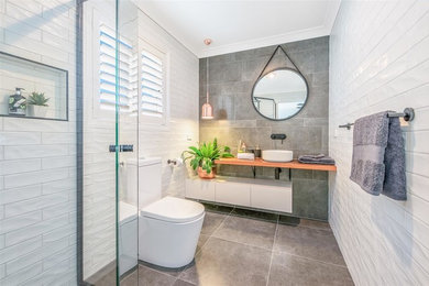 Inspiration for a mid-sized contemporary master bathroom in Brisbane with flat-panel cabinets, white cabinets, an open shower, a one-piece toilet, white tile, ceramic tile, white walls, ceramic floors, a vessel sink, wood benchtops, green floor, an open shower and brown benchtops.