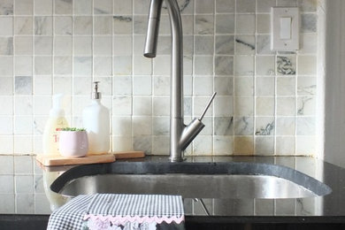 Small minimalist galley limestone floor and gray floor enclosed kitchen photo in New York with an undermount sink, shaker cabinets, black cabinets, quartz countertops, white backsplash, marble backsplash, stainless steel appliances and an island