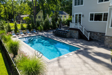Example of a large trendy backyard concrete paver and rectangular lap pool landscaping design in New York
