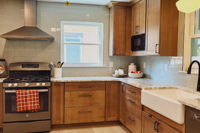 Inspiration for a mid-sized transitional l-shaped vinyl floor and beige floor eat-in kitchen remodel in Other with a farmhouse sink, shaker cabinets, medium tone wood cabinets, quartzite countertops, green backsplash, ceramic backsplash, stainless steel appliances, no island and beige countertops