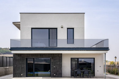 Ejemplo de fachada de casa blanca minimalista de dos plantas con revestimientos combinados y tejado plano