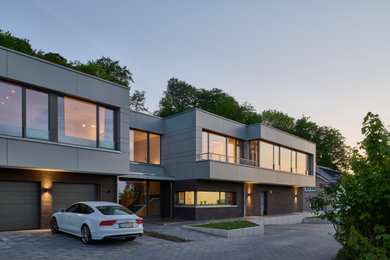 Großes, Zweistöckiges Modernes Haus mit gestrichenen Ziegeln, beiger Fassadenfarbe, Flachdach, Verschalung und schwarzem Dach in Hannover