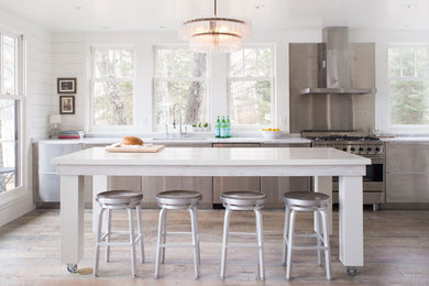 Inspiration for a mid-sized transitional l-shaped open plan kitchen in Minneapolis with flat-panel cabinets, stainless steel cabinets, marble benchtops, stainless steel appliances, with island, an undermount sink, metallic splashback and medium hardwood floors.