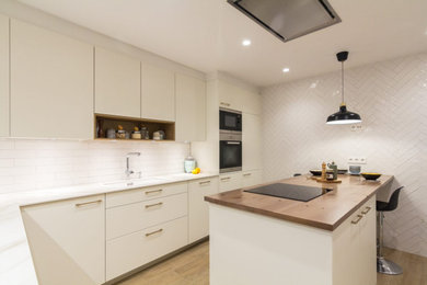 バルセロナにある高級な中くらいな北欧スタイルのおしゃれなキッチン (アンダーカウンターシンク、白いキャビネット、白いキッチンパネル、シルバーの調理設備、磁器タイルの床、白いキッチンカウンター) の写真