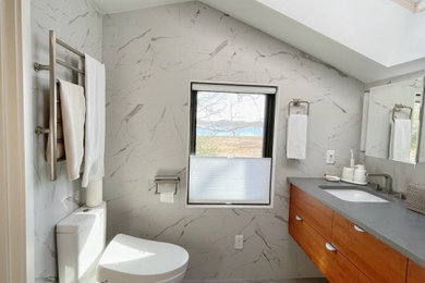 Inspiration for a large modern master white tile and porcelain tile porcelain tile, gray floor, double-sink and vaulted ceiling bathroom remodel in Providence with flat-panel cabinets, medium tone wood cabinets, a bidet, white walls, an undermount sink, quartz countertops, gray countertops and a floating vanity