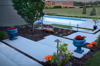 Pool landscaping - large modern backyard concrete and rectangular pool landscaping idea in Omaha